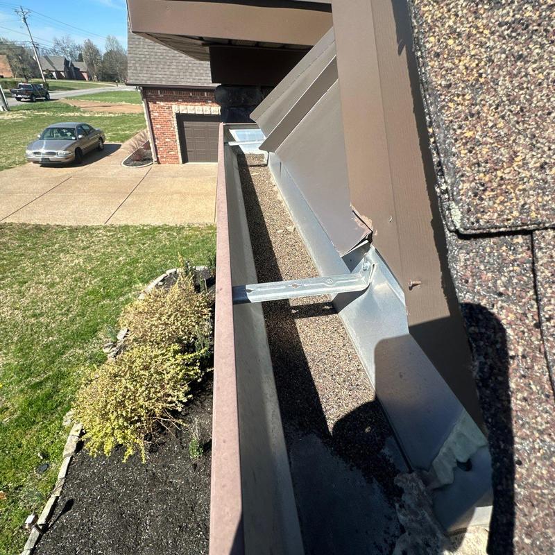 Roof gutter bracket installation near shingle roof edge