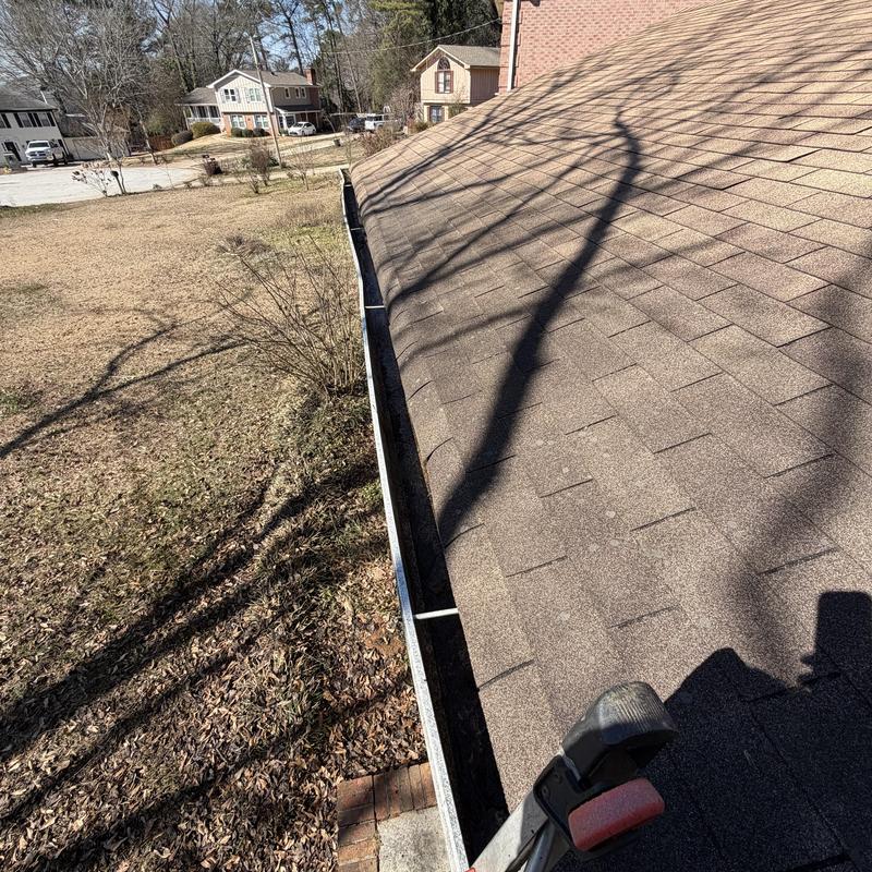 Clean gutter along shingled roof edge outdoors