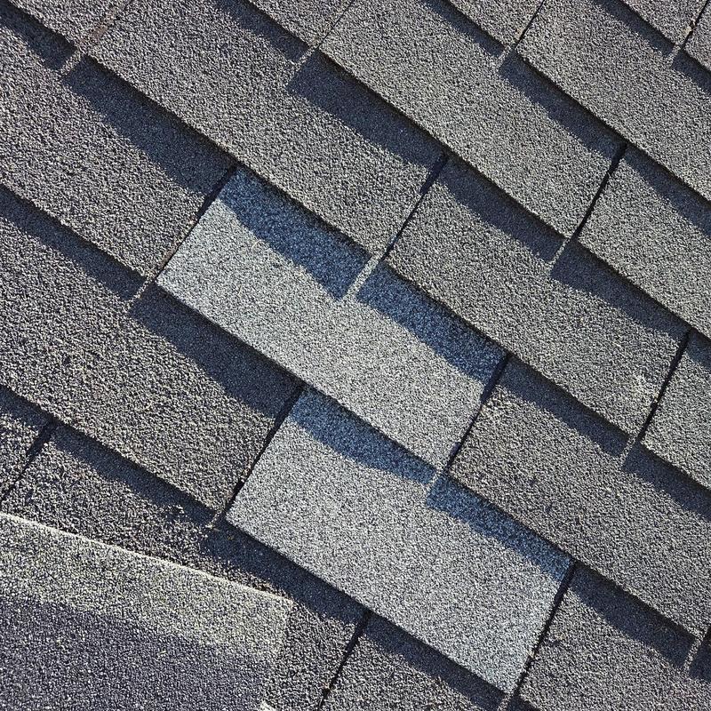 Roof shingles replacement with new decking boards visible