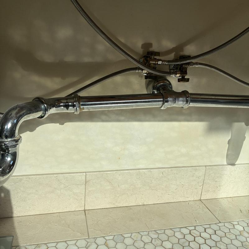 Bathroom sink drain piping and water supply lines under sink