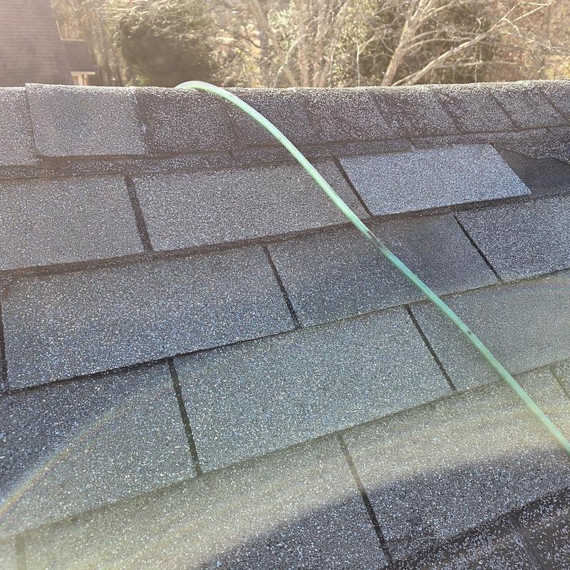 Asphalt shingles and ridge caps on roof with hose