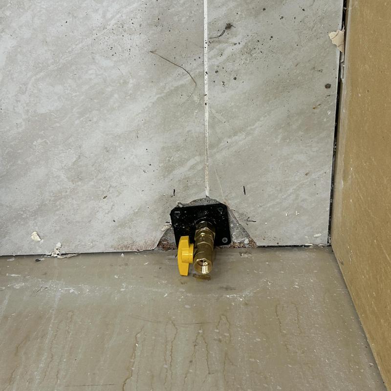 Gas shutoff valve with yellow handle on tile wall