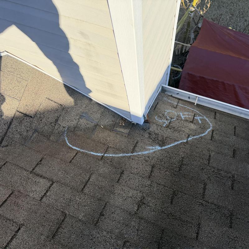 Chimney flashing on shingle roof marked for repair