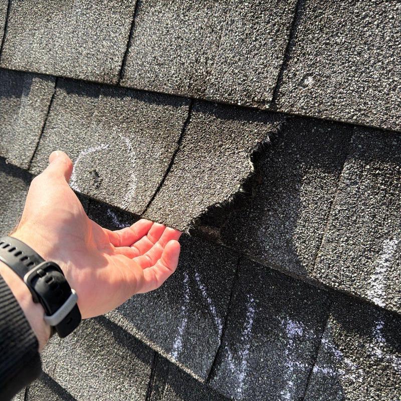 Asphalt roof shingles lifted showing damage and wear