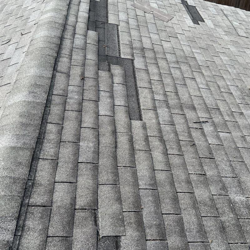 Asphalt shingle roof with damaged and lifted shingles
