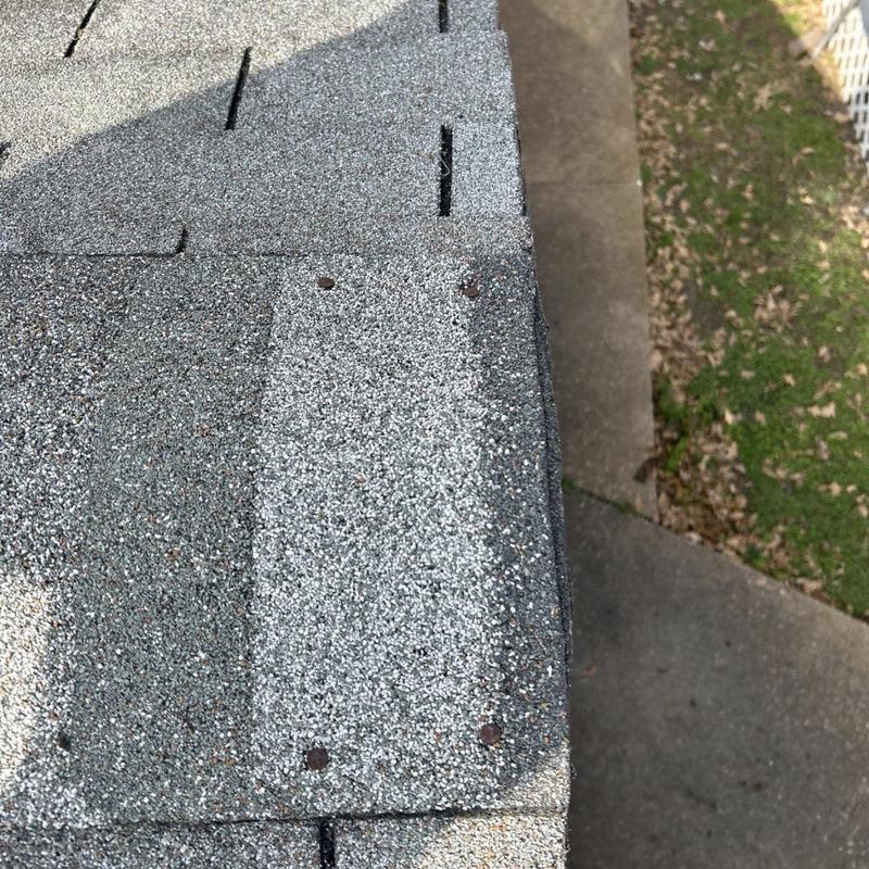 Asphalt shingle roof edge with loose nails and wear