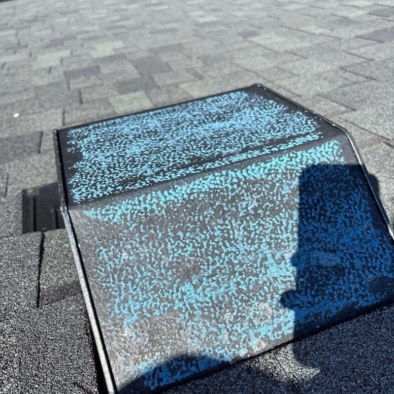 Metal roof vent with hail damage on shingles