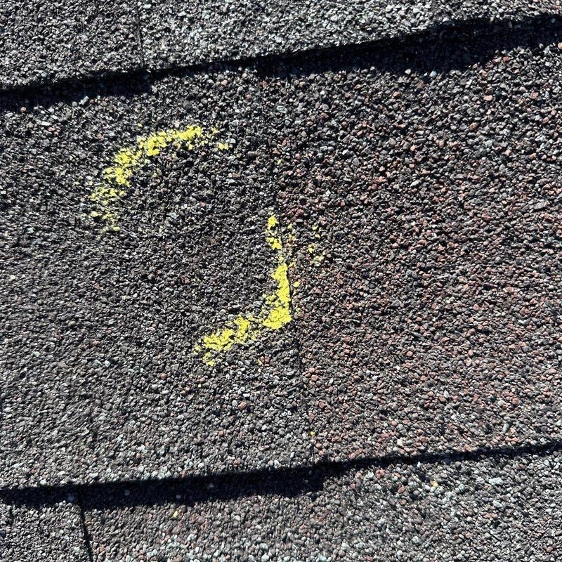 Roof shingle with hail damage marked in yellow
