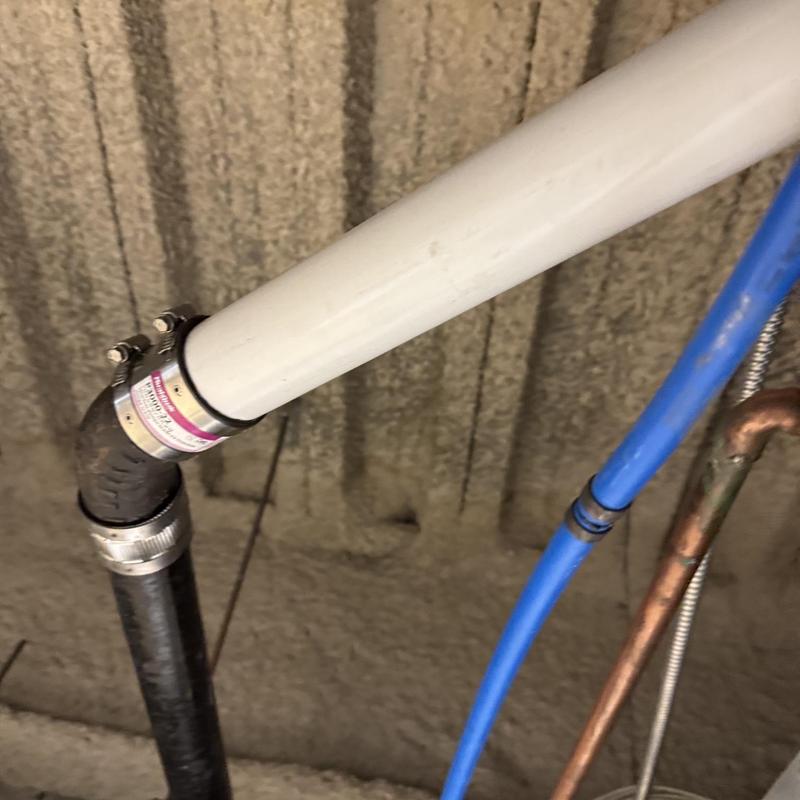 PVC drainage pipe connected to cast-iron pipe with clamps