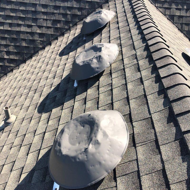 Metal roof vents with heavy hail damage on asphalt shingles