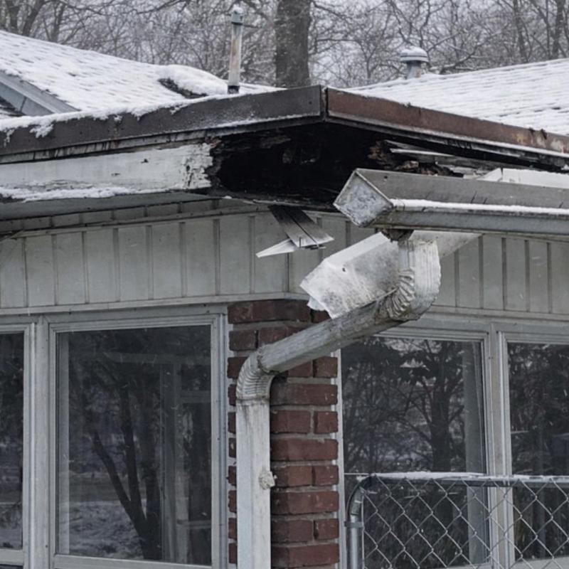 Gutter system with damaged downspout and roof edge decay