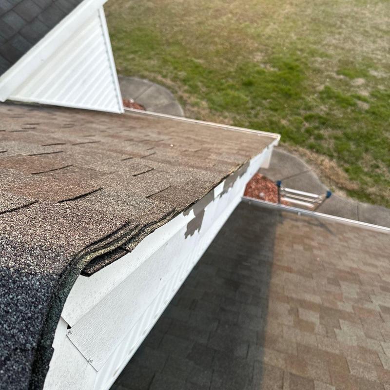 Asphalt shingle roof edge with hail damage and lifted tabs