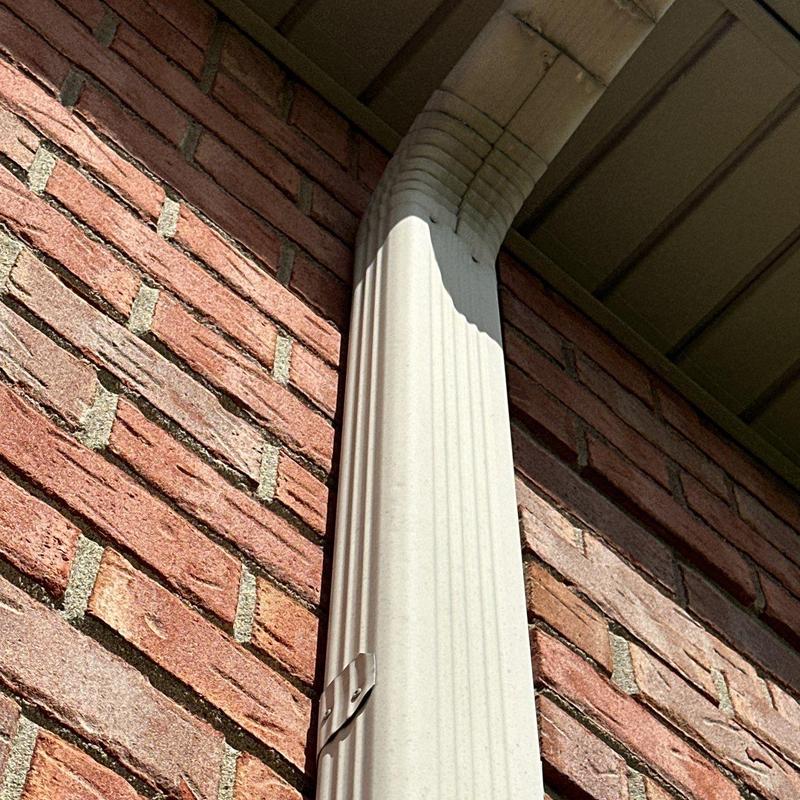 Downspout corner on brick wall under eaves