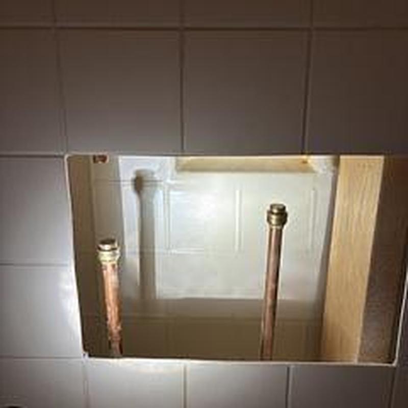 Copper water supply lines behind master bath shower tiled wall