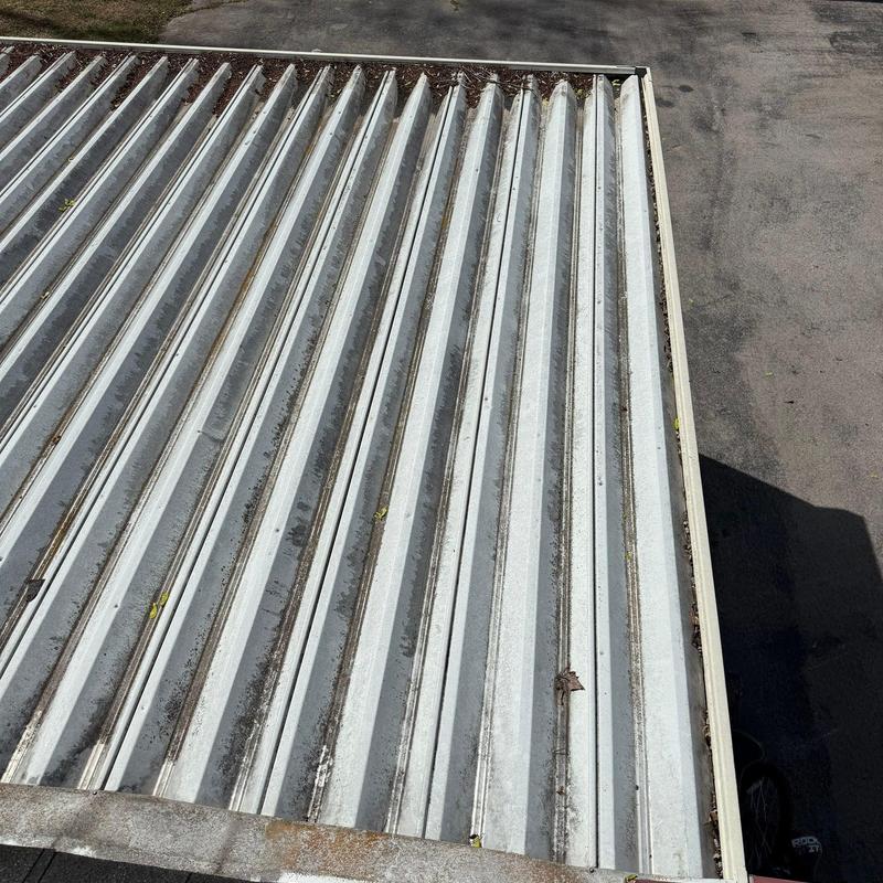 Metal roof panels with debris and dirt buildup