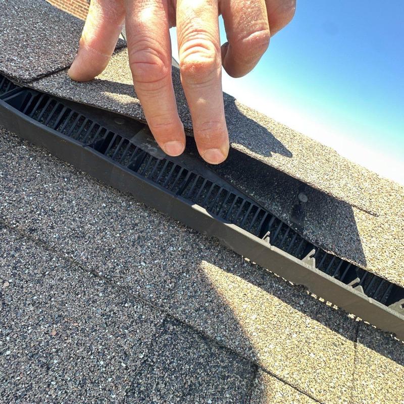 Asphalt shingle ridge vent inspection with hand lifting shingles
