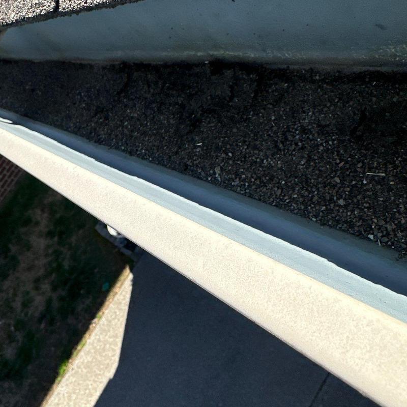 Roof gutter with gravel debris buildup inspection