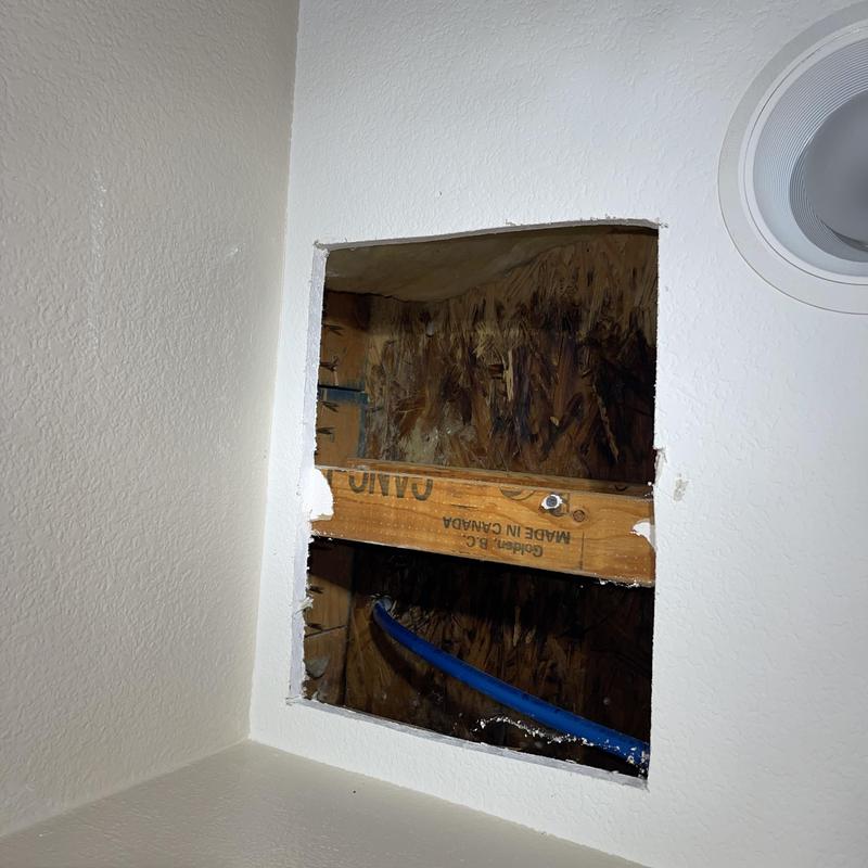 Drywall ceiling access hole showing water damage and plumbing