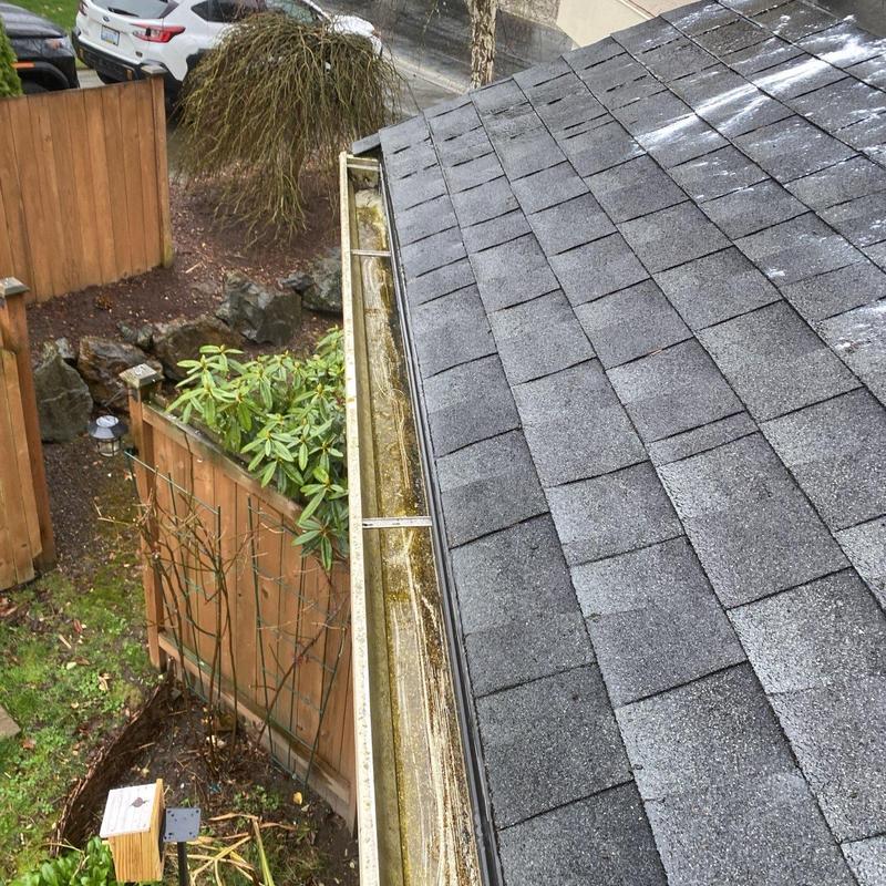 Gutter system clogged with leaves and debris on roof edge