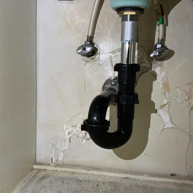 Black plastic P-trap and pop-up drain assembly under sink