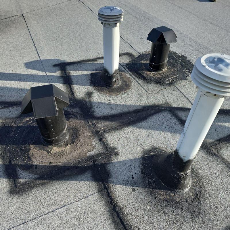 Flat roof vent pipes with worn sealant patches Flat roof vent pipes with worn sealant patches