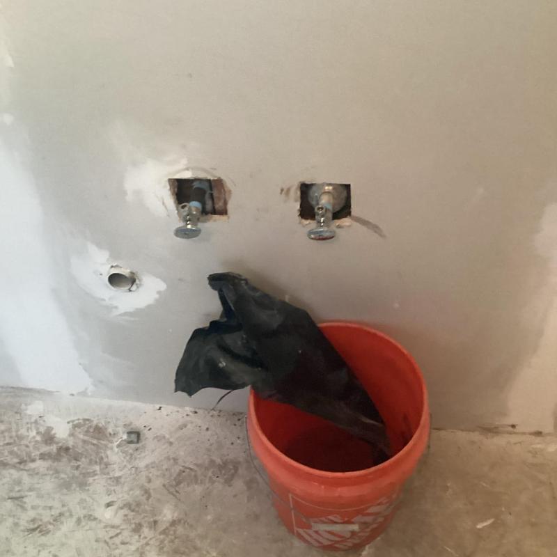 Angle stops installed in kitchen wall with bucket nearby