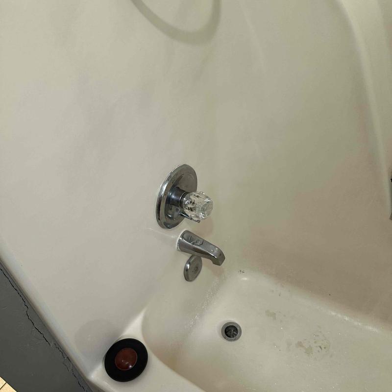 Shower valve and tub faucet in white bathtub