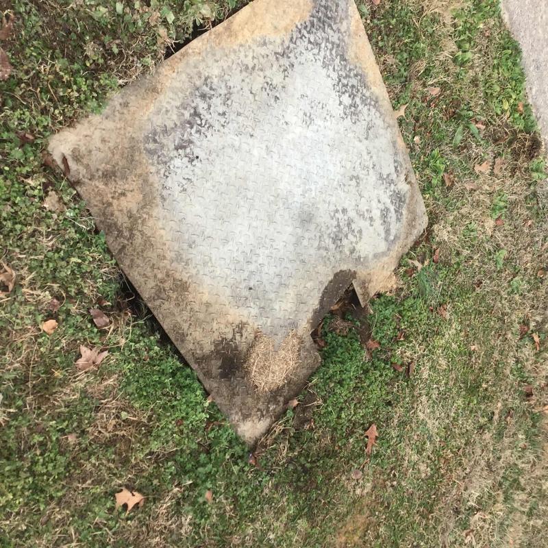 Sewer pump vault cover with dirt and grass surrounding