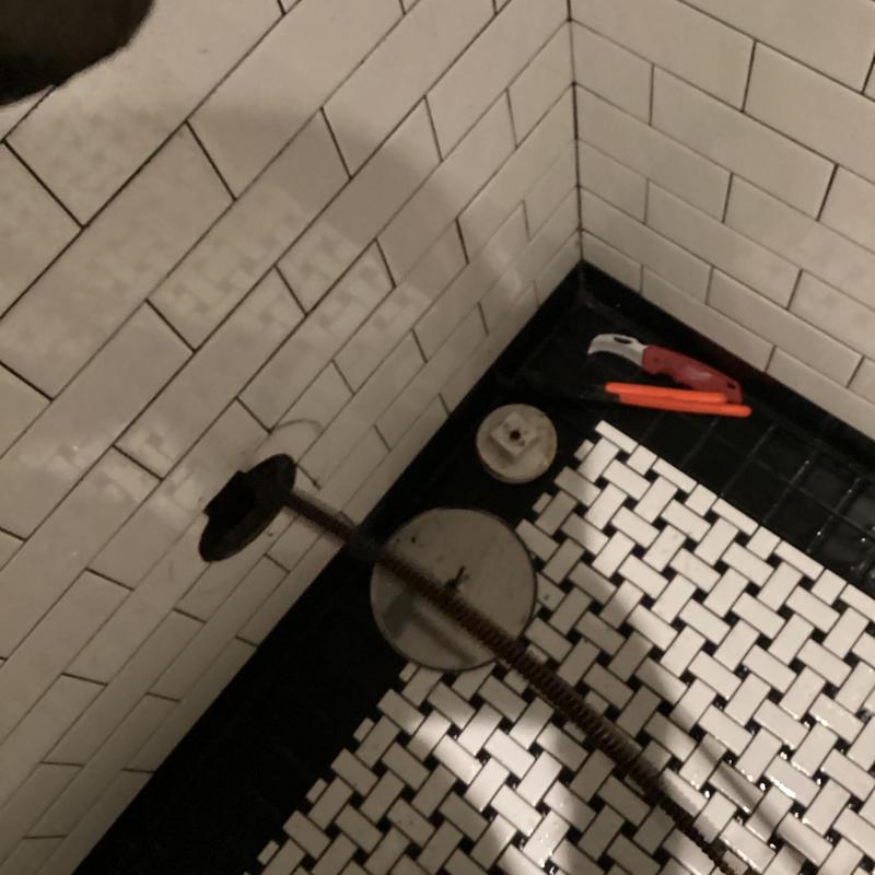 Main drain cleanout and plumbing tools in restroom floor