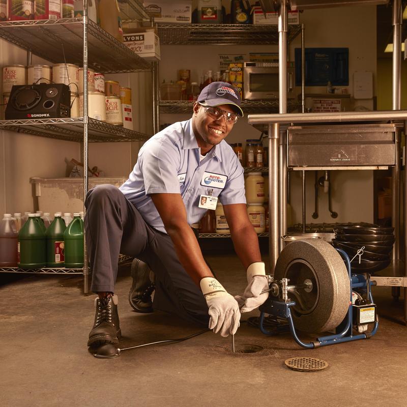 Drain cleaning machine clearing floor drain in kitchen