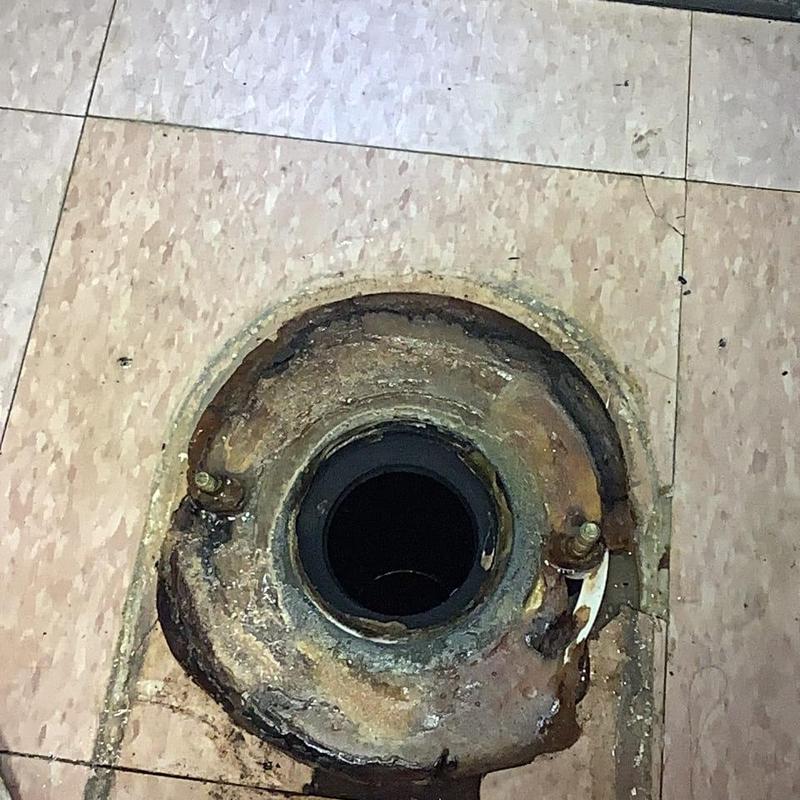Toilet flange and open drain line on tiled floor