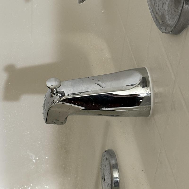 Chrome tub spout with old caulk removed in bathtub