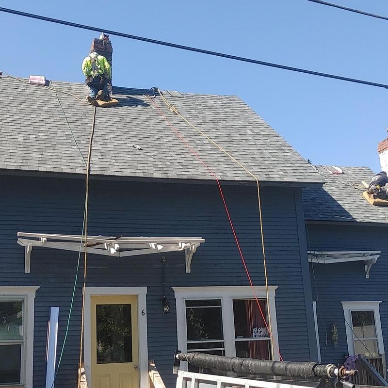 Asphalt shingle roof installation with workers on house