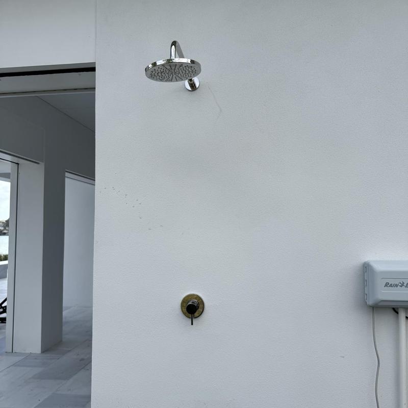 Outdoor shower fixture installed on white wall