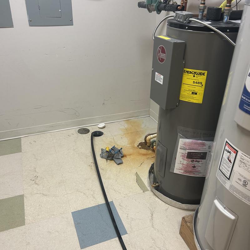 Water heater with rust stain and floor drain hose