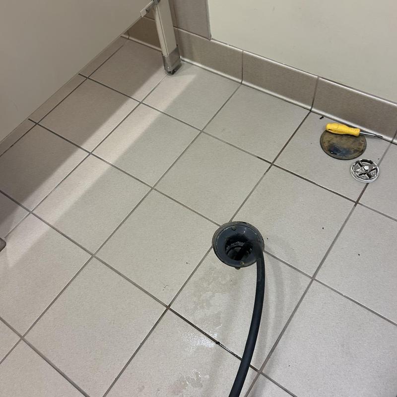 Floor drain hydro-jet cleaning with tools on tiled floor