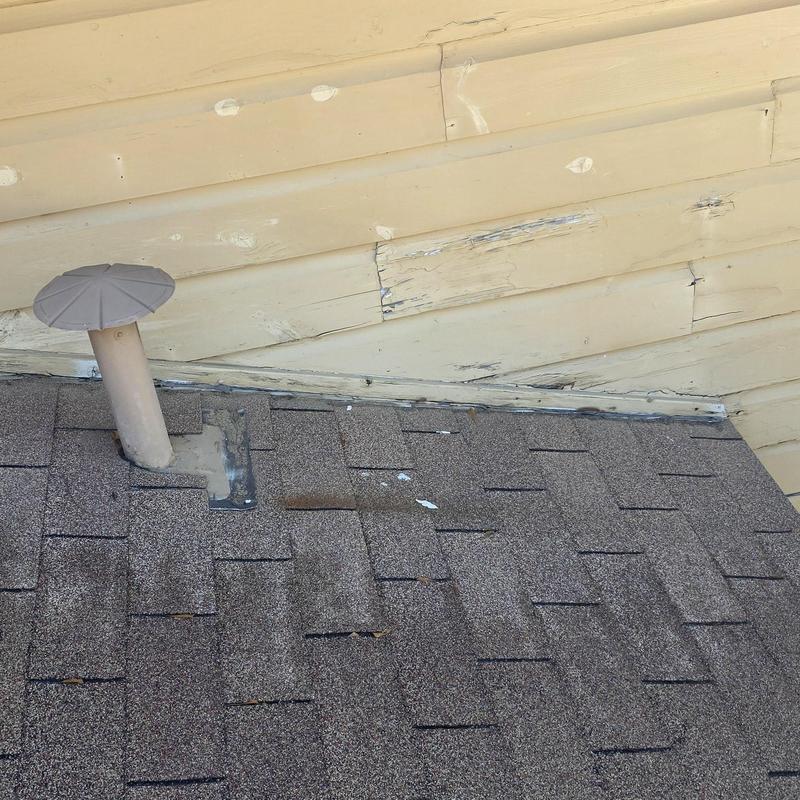 Asphalt roof shingles with hail impact damage near vent pipe