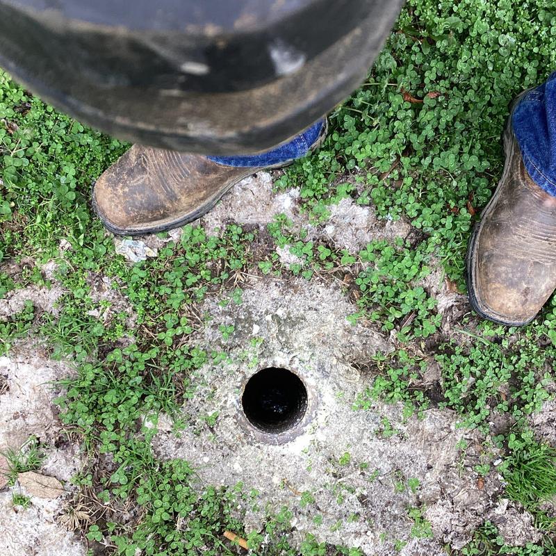 4-inch drain line opening with worker boots nearby