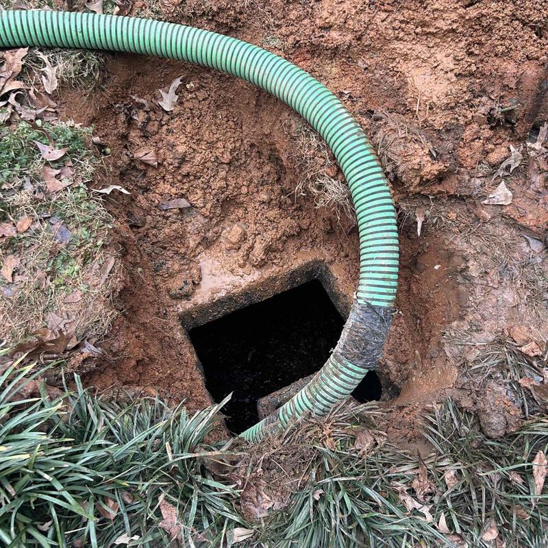 Septic tank with green pumping hose in soil
