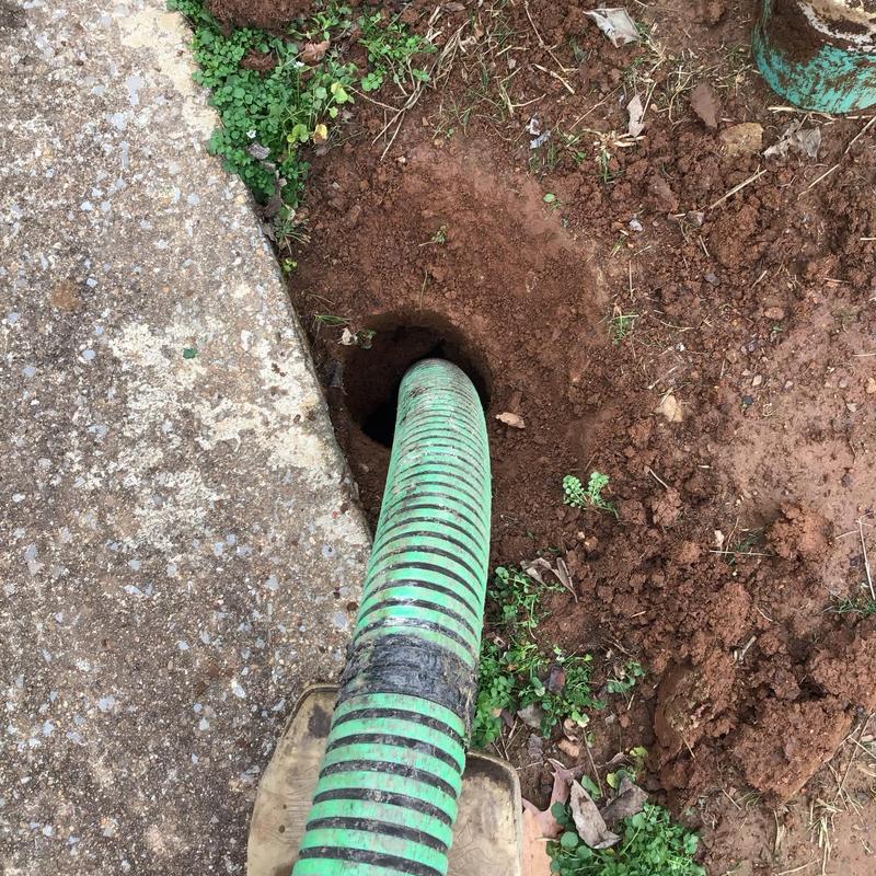 Septic tank riser with hose inserted for pumping
