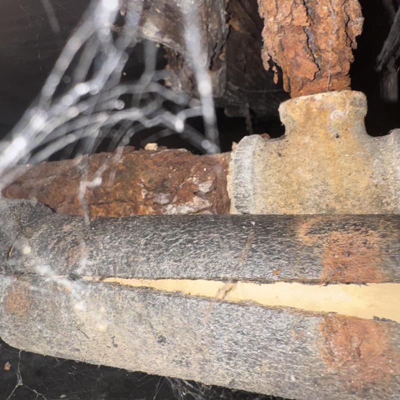 Rusty gas pipe with damaged insulation in crawl space
