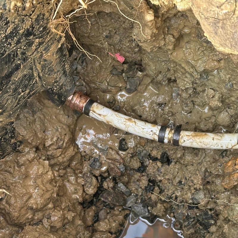 Copper pipe underground with repair clamps in mud Copper pipe underground with repair clamps in mud