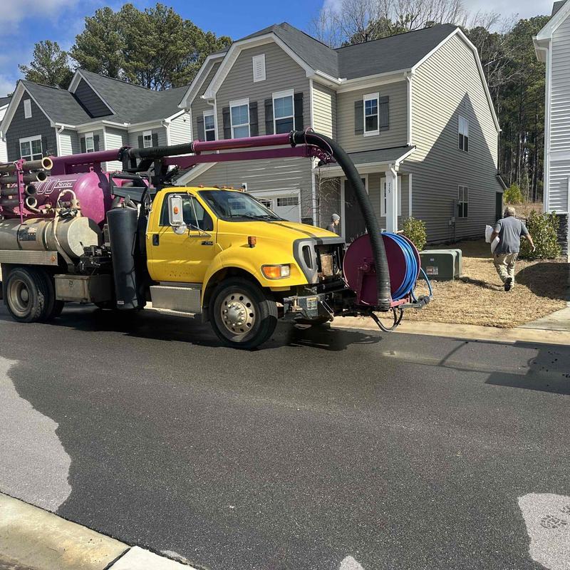 Vacuum truck with piping hose on residential street Vacuum truck with piping hose on residential street