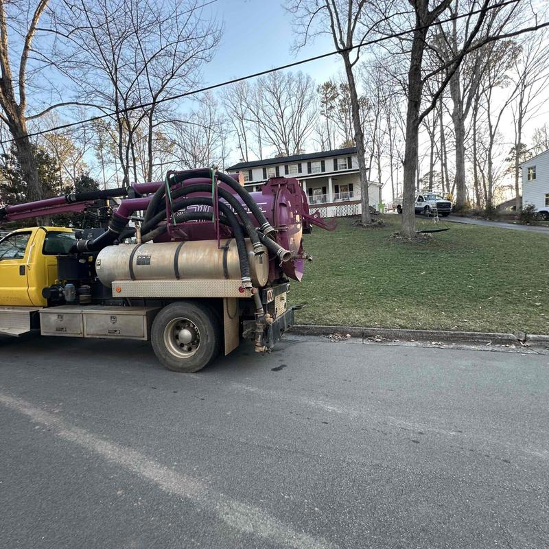 Vacuum truck parked by residential lawn, trees, houses Vacuum truck parked by residential lawn, trees, houses
