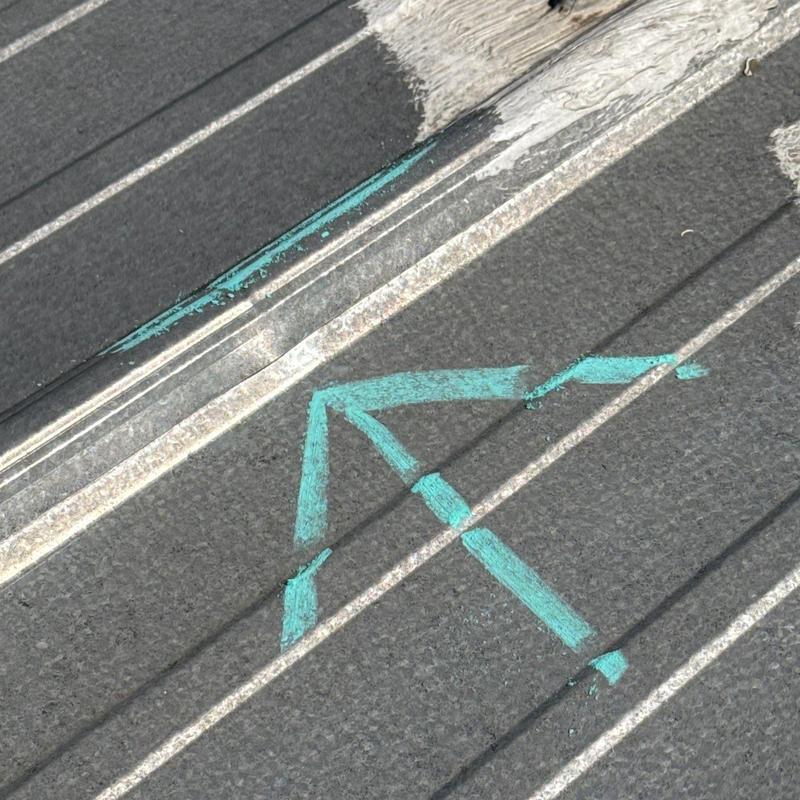 Metal roof panel with hail damage marked in blue