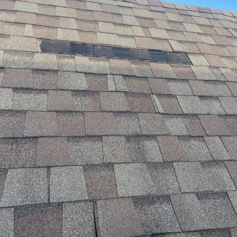 Asphalt shingle roof with damaged and replaced shingles