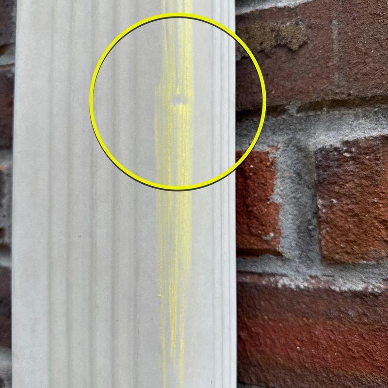 Vinyl siding crack with yellow marking on brick wall