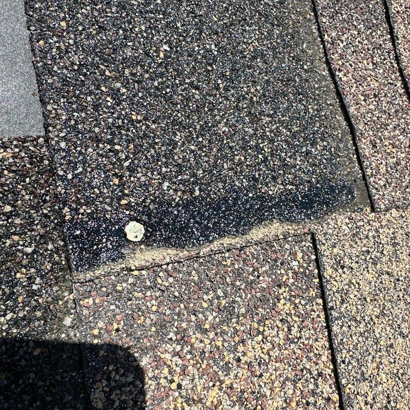 Asphalt shingles with hail damage and nail head exposed