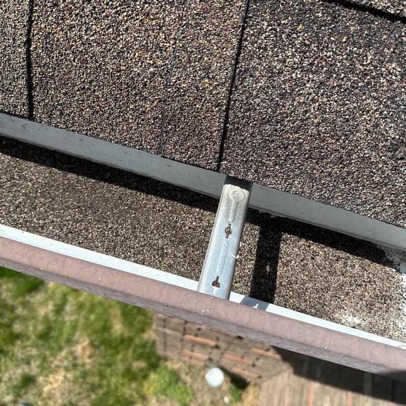 Asphalt shingle roof showing hail damage near gutter system