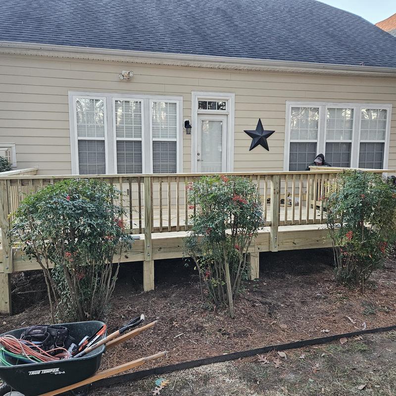 Wooden deck with railing and landscaping in backyard